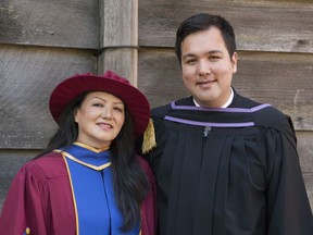 Jocelyne Robinson and son Randy Robinson in their graduation regalia in front of the University of B.C.'s First Nations Longhouse. The mother-and-son duo are graduating from UBC together, their ceremonies a day apart.