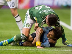 Vancouver Whitecaps' Nicolas Mezquida is taken to the ground by Portland Timbers' Liam Ridgewell during the first half of Saturday's game at B.C. Place.
