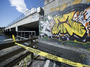 Police tape hangs from a pedestrian walkway under a train bridge in Harbourview Park in North Vancouver, where a body was discovered near Lynn Creek earlier today.