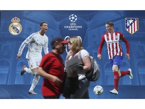 People walk by a billboard portraying Real Madrid's Cristiano Ronald, left, and Athletico Madrid's Fernando Torres, at the Champions Festival event area, in Milan, Italy, Thursday. The Champions League soccer final between Real Madrid and Atletico Madrid will be held at the San Siro stadium on Saturday.