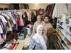 Shawkat Hasan (in back) of the B.C. Muslim Association and Elham Hijazi (front), an association volunteer, pose with Zaid Fawaz, a Syrian refugee, in a storeroom full of donated wares for refugees in Richmond.