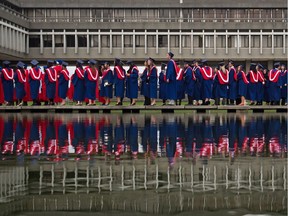 Simon Fraser University students are reflected in a pond as they line up to receive their degrees during a convocation ceremony at the university in Burnaby.
