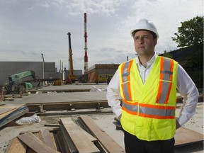 Surrey engineering manager Rob Costanzo is pictured at the partly-constructed biofuels plant with the 70-metre high stack in the background.