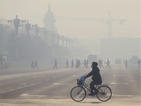 A woman wears a mask as she rides her bicycle along a street on the third day of a 'red alert' for pollution in Beijing last December. Scenes like these have led China's leadership to promise an 'ecological civilization.'