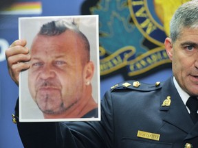 RCMP officer Brian Cantera holds a photo of Bryan Oldham at a news conference in 2012.
