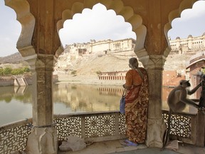 A woman standing on a veranda in Rajasthan with Amber Fort in distance.