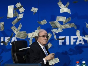 FIFA president Sepp Blatter looks on with fake dollars note flying around him thrown by a protester during a press conference at the football's world body headquarter's on July 20, 2015 in Zurich.