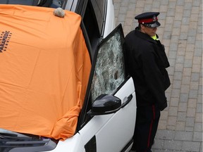 Toronto police stand guard over the white Range Rover in which former Metro Vancouver resident Sukh Deo was shot to death Tuesday. Note the many bullet holes in the driver side window.