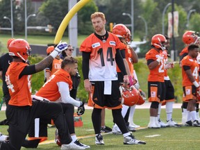 B.C. Lions quarterback Travis Lulay (centre) takes a pointer from receiver Emmanuel Arceneaux (kneeling) during a drill at the CFL team's training camp in Kamloops.