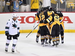 San Jose Sharks captain Joe Pavelski looks forlorn as Pittsburgh Penguins mob Nick Bonino after he scored the ultimately game-winning goal in Game 1 of the Stanley Cup final on Monday.