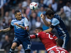Vancouver Whitecaps' Blas Perez, left, and Andrew Jacobson, right, vie for the ball against New England Revolution's Andrew Farrell during second half MLS soccer action in Vancouver on Saturday.