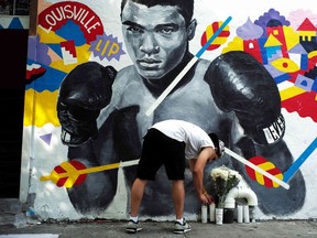A man places a candle under a mural of the later boxer Muhammad Ali in New York on Saturday. Ali, the three-time world heavyweight champion and colourful civil rights activist whose fame transcended the world of sports and made him an iconic figure of the 20th century, died Friday at age of 74, after a long battle with Parkinson's disease.