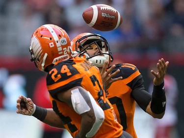 B.C. Lions quarterback Jonathon Jennings, back, bobbles the snap as Jeremiah Johnson watches during the first half of a pre-season CFL football game against the Calgary Stampeders in Vancouver, B.C., on Friday June 17, 2016. THE CANADIAN PRESS/Darryl Dyck ORG XMIT: VCRD102