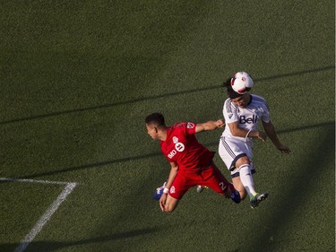 Vancouver Whitecaps' Christian Bolanos, right, tries to direct a header on the goal despite pressure from Toronto FC's Justin Morrow during first half Canadian Cup action in Toronto on Tuesday June 21, 2016.