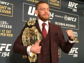 Conor McGregor poses with the UFC featherweight title at the UFC 194 post-fight press conference. E. Spencer Kyte