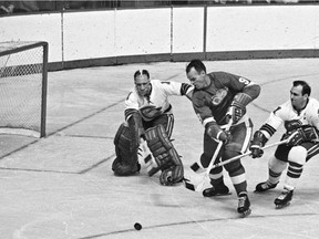 In this Oct. 26, 1967, file photo, California Seals goalie Charlie Hodge, left, knocks the puck away as Detroit Red Wings' star Gordie Howe tries a shot on goal as the Seals' Bob Baun comes in at right during the second period of an NHL hockey game in Detroit.