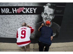 People sign a memorial wall as thousands of people line up to pay their respects to NHL Hall-of-Famer Gordie Howe as the casket rests in the Joe Louis Arena in Detroit, Mich., on Tuesday, June 14, 2016.