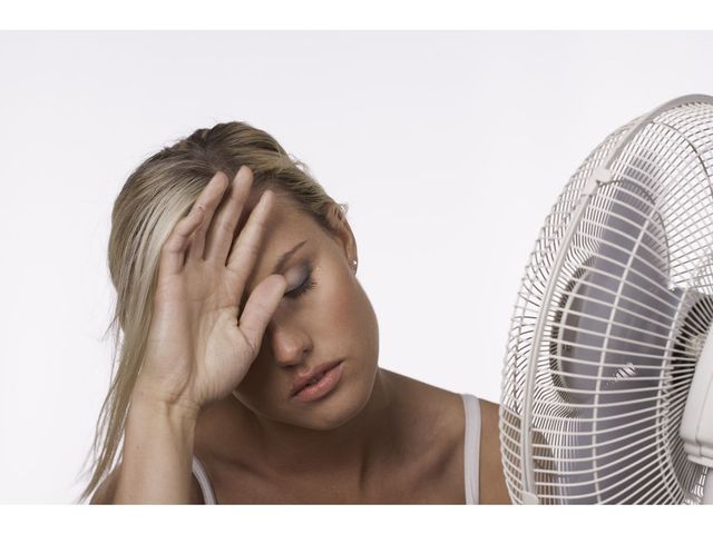Woman cooling down in front of fan. Getty images stock pic. [PNG Merlin Archive]
