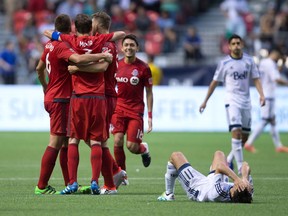 Vancouver Whitecaps' Nicolas Mezquida, bottom right, reacts as Toronto FC's Nick Hagglund, from left, Drew Moor, Ashtone Morgan and Marky Delgado celebrate after winning the Canadian Championship soccer final on aggregate in Vancouver, B.C., on Wednesday June 29, 2016.
