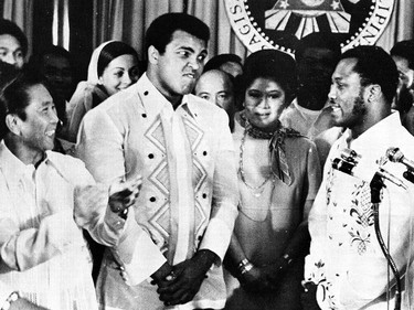 FILE - In this Sept. 18, 1975, file photo, Philippines President Ferdinand Marcos, left, applauds as challenger Joe Frazier, right, makes some remarks about world champion Muhammad Ali, second from left, during their call on Marcos at the Malacanang Palace in Manila, Philippines.  Ali, the magnificent heavyweight champion whose fast fists and irrepressible personality transcended sports and captivated the world, has died according to a statement released by his family Friday, June 3, 2016. He was 74. (AP Photo/Jess Tan, File) ORG XMIT: NY211