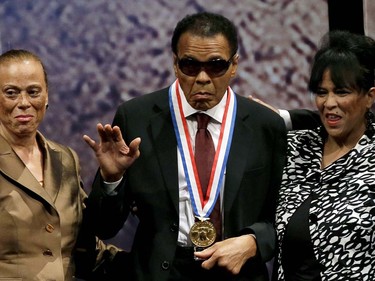 FILE - In this Sept. 13, 2012, file photo, retired boxing champion Muhammad Ali, center, waves alongside his wife Lonnie Ali, left, and his sister-in-law Marilyn Williams, right, after receiving the Liberty Medal during a ceremony at the National Constitution Center in Philadelphia.  Ali, the magnificent heavyweight champion whose fast fists and irrepressible personality transcended sports and captivated the world, has died according to a statement released by his family Friday, June 3, 2016. He was 74. (AP Photo/Matt Slocum, File) ORG XMIT: NY220