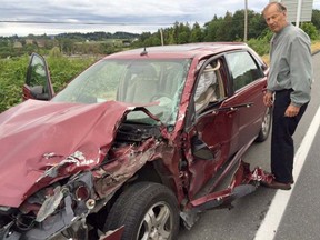 Saanich Coun. Vic Derman stands beside a car that had been carrying him and two other Saanich councillors, which was involved in a crash on the Pat Bay Highway at Keating Cross Road on Thursday morning.