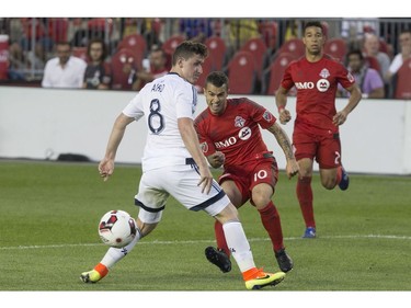 Toronto FC's Sebastian Giovinco, centre, uses Vancouver Whitecaps' Fraser Aird (8) as a shield as he fires a shot towards goal during second half Canadian Cup action in Toronto on Tuesday June 21, 2016.