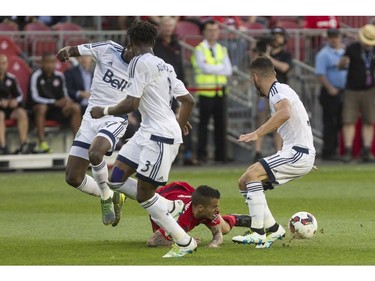 Toronto FC's Sebastian Giovinco, centre, falls to the ground as he takes on a cluster of Vancouver Whitecaps defenders during first half Canadian Cup action in Toronto on Tuesday June 21, 2016.