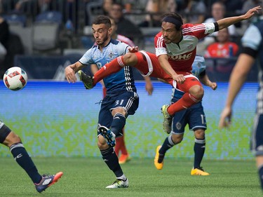 New England Revolution's Daigo Kobayashi, right, leaps to kick the ball away from Vancouver Whitecaps' Russell Teibert during first half MLS soccer action in Vancouver, B.C., on Saturday June 18, 2016. THE CANADIAN PRESS/Darryl Dyck ORG XMIT: VCRD104