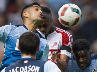 New England Revolution's London Woodberry, back centre, uses his head to score a goal as Vancouver Whitecaps' Matias Laba, left, and Jordan Smith, right, defend during the first half.