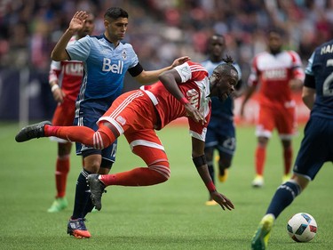 New England Revolution's Kei Kamara, centre, is upended by Vancouver Whitecaps' Matias Laba, bck left, during first half MLS soccer action in Vancouver, B.C., on Saturday June 18, 2016. THE CANADIAN PRESS/Darryl Dyck ORG XMIT: VCRD102