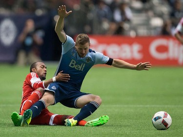 New England Revolution's Teal Bunbury, left, brings down Vancouver Whitecaps' Jordan Harvey during first half MLS soccer action in Vancouver, B.C., on Saturday June 18, 2016. THE CANADIAN PRESS/Darryl Dyck ORG XMIT: VCRD101