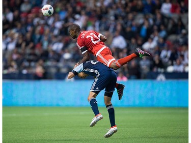 New England Revolution's Jose Goncalves, top, jumps over the back of Vancouver Whitecaps' Blas Perez to get to the ball during second half MLS soccer action in Vancouver, B.C., on Saturday June 18, 2016. THE CANADIAN PRESS/Darryl Dyck ORG XMIT: VCRD113