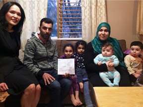 Vancouver East MP Jenny Kwan with Syrian refugee Amer Alhendawi, his wife and four of their five children. Alhendawi, holding a government document detailing the amount he still owes on the loan to fly him and his family to Canada, testified about his inability to get into English-language classes.