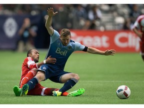 New England Revolution's Teal Bunbury brings down fullback Jordan Harvey. The Whitecaps have been slipping up too much lately.