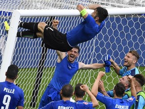 Italy's goalkeeper Gianluigi Buffon (top) climbs to the goal's crossbar as they celebrate at the end of the Euro 2016 round of 16 football match between Italy and Spain at the Stade de France stadium in Saint-Denis, near Paris, on June 27, 2016.