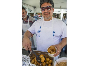 John Kantarakias serves up loukomathes, which are honey doughnuts, at Greek Day on West Broadway in Vancouver, B.C., June 26, 2016.