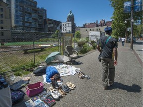 A man selling some old shoes and used books sleeps on the sidewalk on East Hastings in Vancouver on Tuesday.