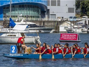 A team pass by a sailboat moored in False Creek in Vancouver, B.C., Sunday, June 5, 2016.