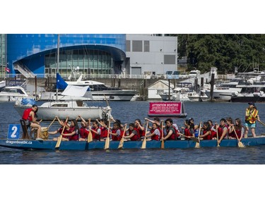 A team pass by a sailboat moored in False Creek in Vancouver, B.C., Sunday, June 5, 2016.