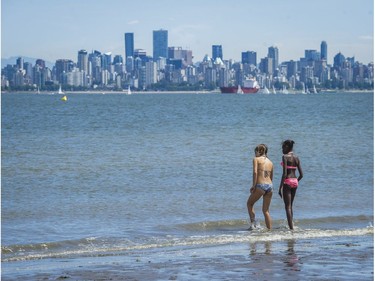Julia Nelson, left, and Cynthia Ouchi wade into the ocean on Spanish Banks beach in Vancouver, B.C., Sunday, June 5, 2016.