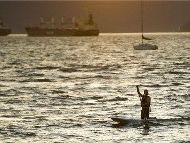 A man makes his way to shore at sunset at Kits Beach in Vancouver, B.C., June, 4, 2016.