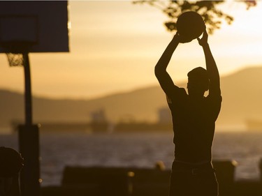 A man shoots a ball while play basketball at Kits Beach in Vancouver, B.C., June, 4, 2016.