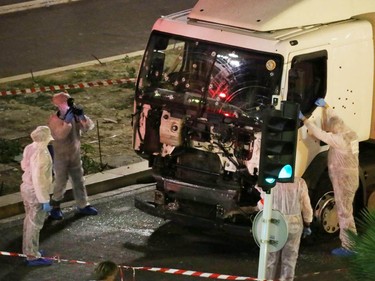 Authorities investigate a truck after it plowed through Bastille Day revelers in the French resort city of Nice, France, Thursday, July 14, 2016. France was ravaged by its third attack in two years when a large white truck mowed through revelers gathered for Bastille Day fireworks in Nice, killing at dozens of people as it bore down on the crowd for more than a mile along the Riviera city's famed seaside promenade.