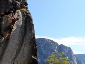 A climber scales 'Neat and Cool' route in the Smoke Bluffs, with the iconic Stawamus Chief looming in the background, near Squamish.