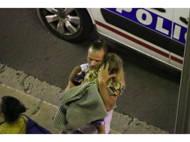 A man holds a child after a truck plowed through Bastille Day revelers in the French resort city of Nice, France, Thursday, July 14, 2016. France was ravaged by its third attack in two years when a large white truck mowed through revelers gathered for Bastille Day fireworks in Nice, killing at dozens of people as it bore down on the crowd for more than a mile along the Riviera city's famed seaside promenade.