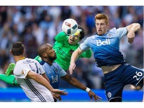 Los Angeles Galaxy goalkeeper Brian Rowe, back left, knocks the ball down with his hands as Vancouver Whitecaps’ Tim Parker, right, tries to get his head on it in front of teammate Kendall Waston, second left, during the first half of an MLS soccer game in Vancouver, B.C., on Saturday April 2, 2016.