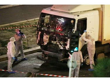 Authorities investigate a truck after it plowed through Bastille Day revelers in the French resort city of Nice, France, Thursday, July 14, 2016. France was ravaged by its third attack in two years when a large white truck mowed through revelers gathered for Bastille Day fireworks in Nice, killing at dozens of people as it bore down on the crowd for more than a mile along the Riviera city's famed seaside promenade.