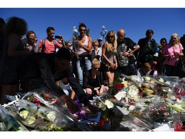 People visit the scene and lay tributes to the victims of a terror attack on the Promenade des Anglais on July 15, 2016 in Nice, France. A French-Tunisian attacker killed 84 people as he drove a lorry through crowds, gathered to watch a firework display during Bastille Day Celebrations. The attacker then opened fire on people in the crowd before being shot dead by police.