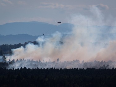 A helicopter prepares to drop water on a fire burning at Burns Bog in Delta on Sunday, July 3, 2016.